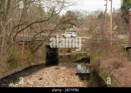 Eine Betonbrücke mit einem Motion Blurred Car darauf, darunter ein Creek Stockfoto