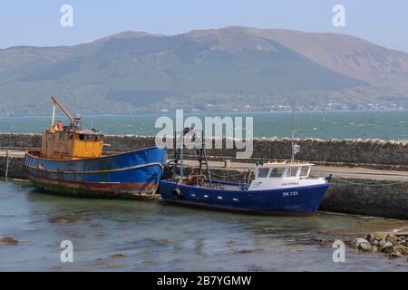 Zwei irische Fischerboote, die am sonnigen Tag auf Sand am Steinkai des Hafenhafens am Greer's Quay bei Omeath am Carlingford Lough ruhen. Stockfoto