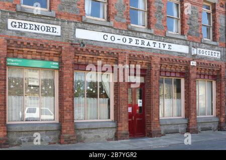 Altes viktorianisches Ladengebäude aus Backstein in Irland, das Gebäude der Greenore Co-Operative Society beherbergt ein Postamt im Hafendorf Greenore, Louth. Stockfoto