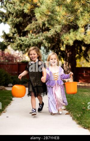 Mädchen in Halloween-Kostümen laufen auf dem Weg Stockfoto