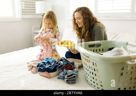 Mutter und Tochter faltende Wäsche auf dem Bett Stockfoto