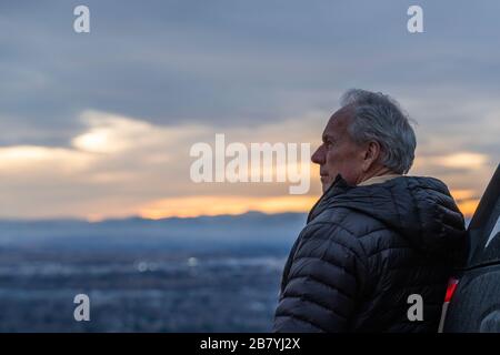 Älterer Mann, der während des Sonnenuntergangs die Aussicht betrachtet Stockfoto