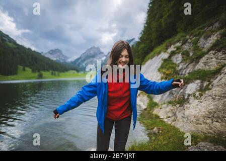 Lächelnde junge Frau in blauer Jacke am See Stockfoto