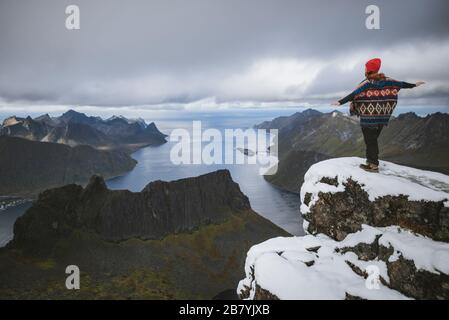 Junge Frau in rotem Hut und Pullover auf verschneiten Berg Stockfoto