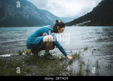 Junge Frau kauert See Stockfoto