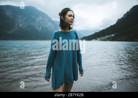 Junge Frau in blauem Pullover am See Stockfoto