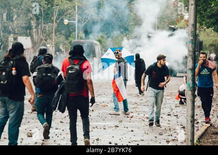 SANTIAGO, CHILE - 8. NOVEMBER 2019 - Demonstranten schützen sich vor Bereitschaftspolizisten während der Proteste gegen die Regierung von Sebastian Pinera, denn Stockfoto