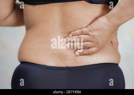 Asiatische Frauen mittleren Alters berühren sich und fühlen Schmerzen im Rücken: Gesundes medizinisches Konzept. Stockfoto