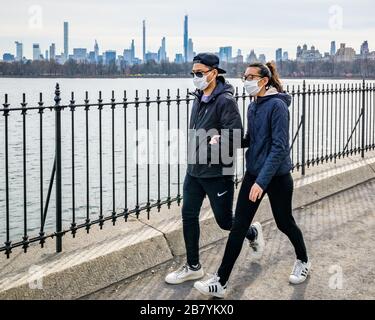 New York, USA, 18. März 2020. Während der Coronavirus-Krise tragen die Menschen Gesichtsmasken, während sie neben dem Central Park Reservoir in der Stadt New York spazieren gehen. Stockfoto