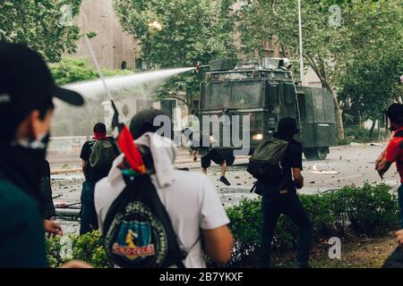 SANTIAGO, CHILE - 8. NOVEMBER 2019 - Molotov Cocktail wird bei den Protesten gegen die Regierung Sebas zur Wasserwerfer der Bereitschaftspolizei gestartet Stockfoto