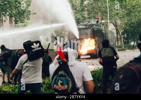 SANTIAGO, CHILE - 8. NOVEMBER 2019 - Molotov Cocktail wird bei den Protesten gegen die Regierung Sebas zur Wasserwerfer der Bereitschaftspolizei gestartet Stockfoto