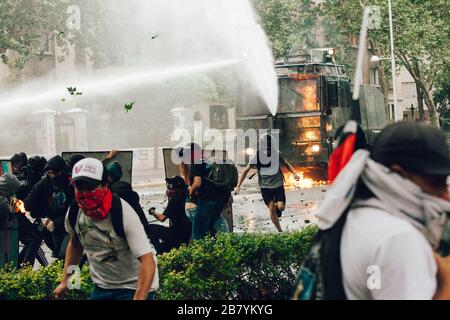 SANTIAGO, CHILE - 8. NOVEMBER 2019 - Molotov Cocktail wird bei den Protesten gegen die Regierung Sebas zur Wasserwerfer der Bereitschaftspolizei gestartet Stockfoto