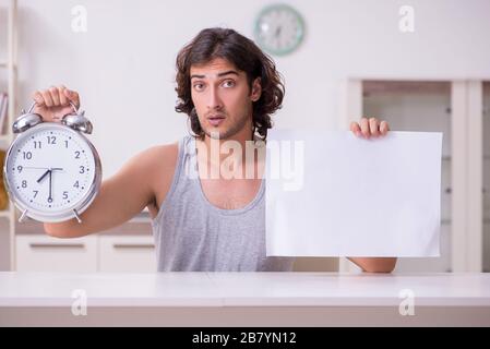 Junger Mann, der zu Hause leeres Papier hält Stockfoto