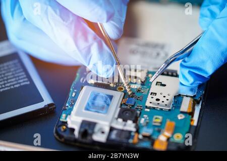 Techniker repariert die Mikrokreislauf-Hauptplatine der Smartphone-Elektronik: Computer, Hardware, Mobiltelefon, Upgrade, Reinigungskonzept. Stockfoto