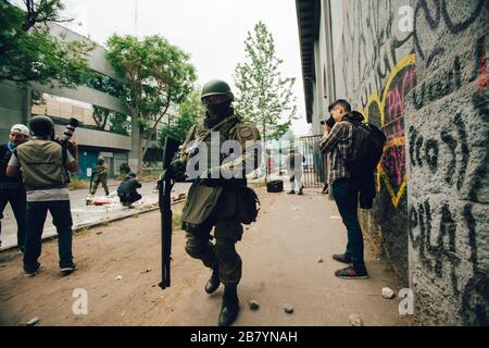 SANTIAGO, CHILE - 8. NOVEMBER 2019 - Einsatz von Anti-Aufruhr-Schrotflinten durch die Polizei, um Demonstranten zu zerstreuen, die eine Kirche umrandeten Stockfoto