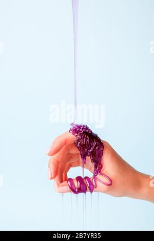 Süße Karamellpaste für die violette Farbe an der weiblichen Hand, Touch Sensative kreative Idee, Haarentfernungskonzept, Kosmetikindustrie, Banner-Flyer c Stockfoto