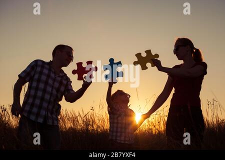 Glückliche Familie, die zum Sonnenuntergang im Park spielt. Leute, die Spaß auf dem Feld haben. Das Konzept des Kindes ist bereit zur Schule zu gehen. Stockfoto