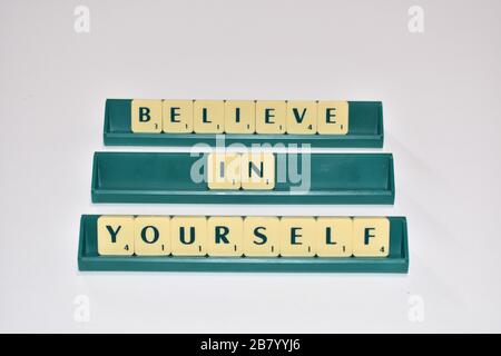 Scrabble Spielsteine sagen, glauben Sie an sich. Motivationszitat Scrabble blockiert Briefe Grauer Hintergrund Lebenszitat induzieren Alphabet. Stockfoto