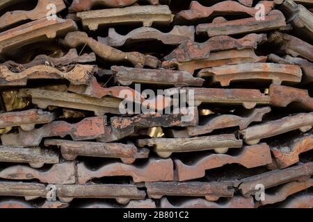 Die Struktur der alten Dachziegel ist verschmutzt und von grünem Moos überzogen Stockfoto