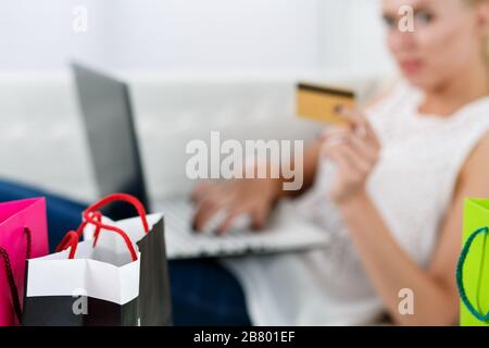 Blonde Frau, die Einkäufe über Internet bezahlt, Kreditkarte Stockfoto