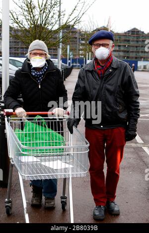 Gloucester, Großbritannien. März 2020. Ein Paar kommt mit Gesichtsmasken an, während Käufer zum Sainsburys Gloucester Quays Store kommen, um die frühe Eröffnung zu besuchen, die auf ältere und verletzliche Käufer aufgrund des Covid-19-/Coronavirus Ausbruchs in Großbritannien abzielt. . Mehr als 200 Käufer kamen in weniger als einer Stunde. Kredit: Andrew Higgins/Thousand Word Media Ltd/Alamy Live News Stockfoto