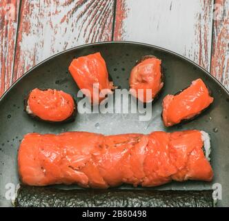 Verschiedene Rollen und Sushi auf einem schönen runden Teller oder Tablett auf einem Holztisch in einem Restaurant Makro gedreht Twisted, aber nicht gehackt Stockfoto