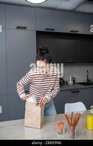 Junge Frau packt Mittagskasten in der Küche aus Stockfoto