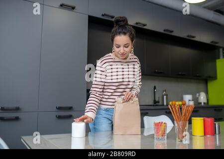 Junge Frau, die die Lunchbox am Tisch auspackt Stockfoto