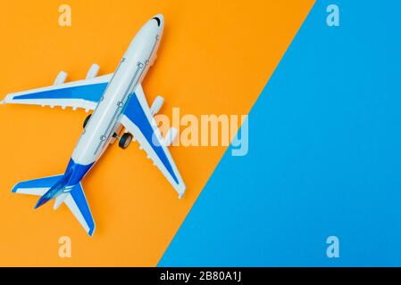 Online-Buchungs-Konzept. Flugzeugmodell und Reisepass auf gelbem und orangefarbenem Hintergrund. Abstrakte Landebahn. Stockfoto