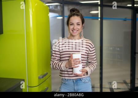 Junge Frau, die in der Küche steht und asiatische Essenskiste hält Stockfoto