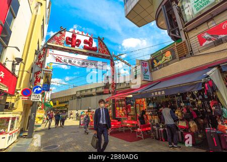 Tokio, Japan - 18. April 2017: asiatischer Geschäftsleute mit Maske am Eingang des beliebten Straßenmarktes Ameya-Yokocho. Verkaufsstände, Geschäfte, Restaurants, Straße Stockfoto