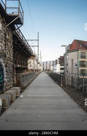 Langer gepflasterter Weg neben den Bögen eines Viadukts unter Ein wolkig Himmel Stockfoto