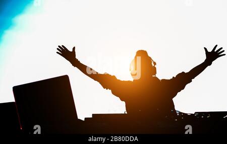 Silhouette des dj-Mischens im Freien mit hinterer Sonneneinstrahlung - Porträt des Discjockey, das trendige Musik für Menschen auf Strandparty bei Sonnenuntergang spielt - Spaß, Sommer, Stockfoto