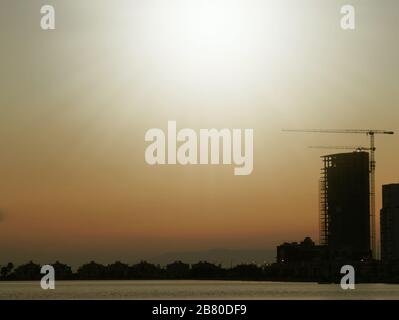 Bau- und Ski-Scraper-Gebäude und Kran gegen bunten Himmel mit Sonne. Baukonzept. Stockfoto