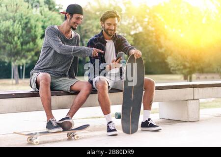 Junge Skater haben Spaß mit Smartphone mit Hintergrundbeleuchtung - beste Freunde teilen Freizeit mit neuer Trendtechnologie - Technology Suchtkonzept Stockfoto