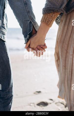 Die Hände eines Paares vor dem Hintergrund des Meeres Strecken sich aufeinander. Stockfoto