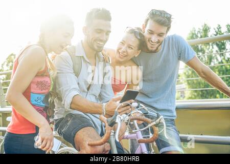 Fröhliche Freunde, die mit Smartphone Videos im Freien ansehen - Jugendliche teilen Medien in neuem sozialen Netzwerk - Konzept für Jugend- und Technologietrends - Stockfoto