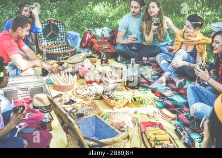 Fröhliche Freunde, die im Picknick im Freien Wein essen und trinken - junge Trendsleute, die Spaß am Naturessen haben und gemeinsam lachen - Hauptaugenmerk auf Mädchen Stockfoto