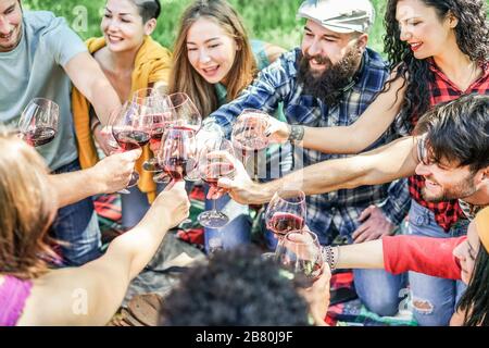 Fröhliche Studenten jubeln mit Weingläsern beim Picknick-Mittagessen im Freien - junge Freunde haben Spaß beim Toast und Essen im Stadtpark - Jugend, Essen und fr Stockfoto