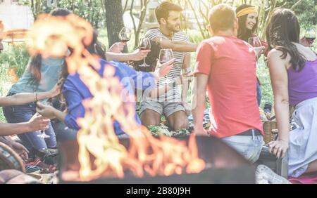 Eine Gruppe von Freunden, die im Freien Picknick mit Grill im Stadtpark machen - junge Leute, die beim Abendessen im Hinterhof Grillgerichte und Wein essen - konzentrieren sich auf sein Stockfoto