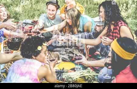 Fröhliche Millennials Freunde trinken und essen beim Picknink-Abendessen im Freien - Junge Leute haben Spaß beim Essen in der Natur - Freundschaft, Jugend-Lebensstil a Stockfoto