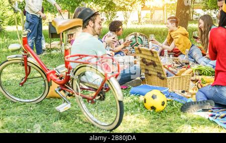 Fröhliche Freunde machen Picknick im Stadtpark im Freien - junge Trend-Leute trinken Wein und essen zusammen draußen - konzentrieren sich auf Top-Center Mädchen und Mann c