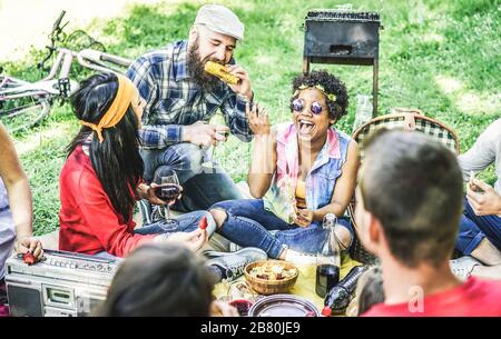 Gruppe glücklicher Freunde, die Spaß am Grillpicknick im Freien haben - junge, vielseitige Kulturstudenten, die im Naturpark zu Abend essen - Jugend, Zusammenfassung Stockfoto