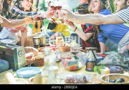 Fröhliche Freunde jubeln mit Weingläsern beim Pic-nic Mittagessen im Freien - junge Studenten haben Spaß beim Toast und Essen auf die Natur - Lebensmittel- und Jugendkonz Stockfoto