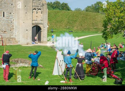 Re-enactors, die einen Langbogen, eine Armbrust, Musket und eine Kanone auf Castle Rising in Norfolk feuern Stockfoto