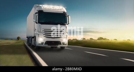 Schneller, bewegter Truck bei voller Beleuchtung bei Sonnenuntergang in einer schönen Landschaft. Deutschland Stockfoto