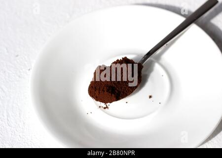 Gemahlener Kaffee in einem Löffel auf einem weißen Untertopf. Kaffee Machen. Stockfoto