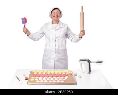 Fröhliche fröhliche Bäckerin, die Werkzeuge für eine Bäckerei in ihren Händen hält. Isoliert auf weißem Hintergrund Stockfoto