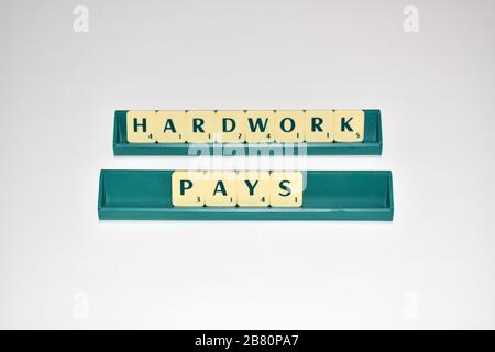 Scrabble Fliesen buchstabieren harte Arbeit zahlt. Motivationszitat Scrabble blockiert Briefe Grauer Hintergrund Lebenszitat induzieren Alphabet. Stockfoto