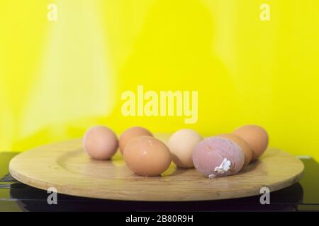 Gekochte Eier auf Holzplatte, gelber Hintergrund, Kopierraum. Stockfoto
